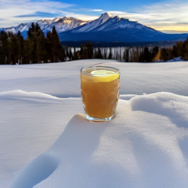 A Hot Toddy made with Sip Steeple Organic Black Tea sitting on a bed of snow with mountains in the background