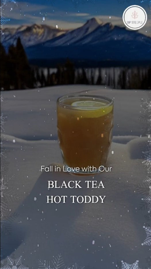 A Hot Toddy made with Sip Steeple Organic Black Tea sitting on a bed of snow with mountains in the background
